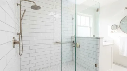 A white subway tiled shower behind a frameless glass screen